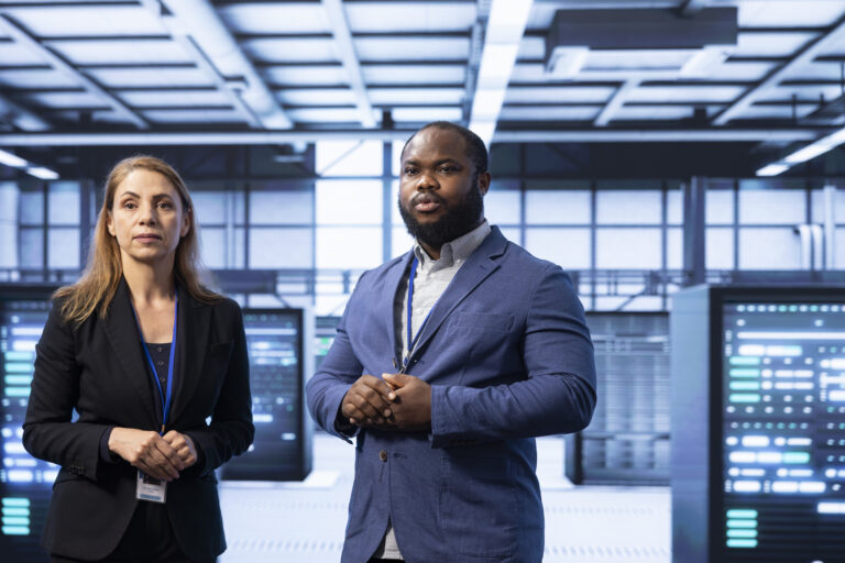 Coworkers in server room looking for technical bugs Black Man and white woman standing in data center
