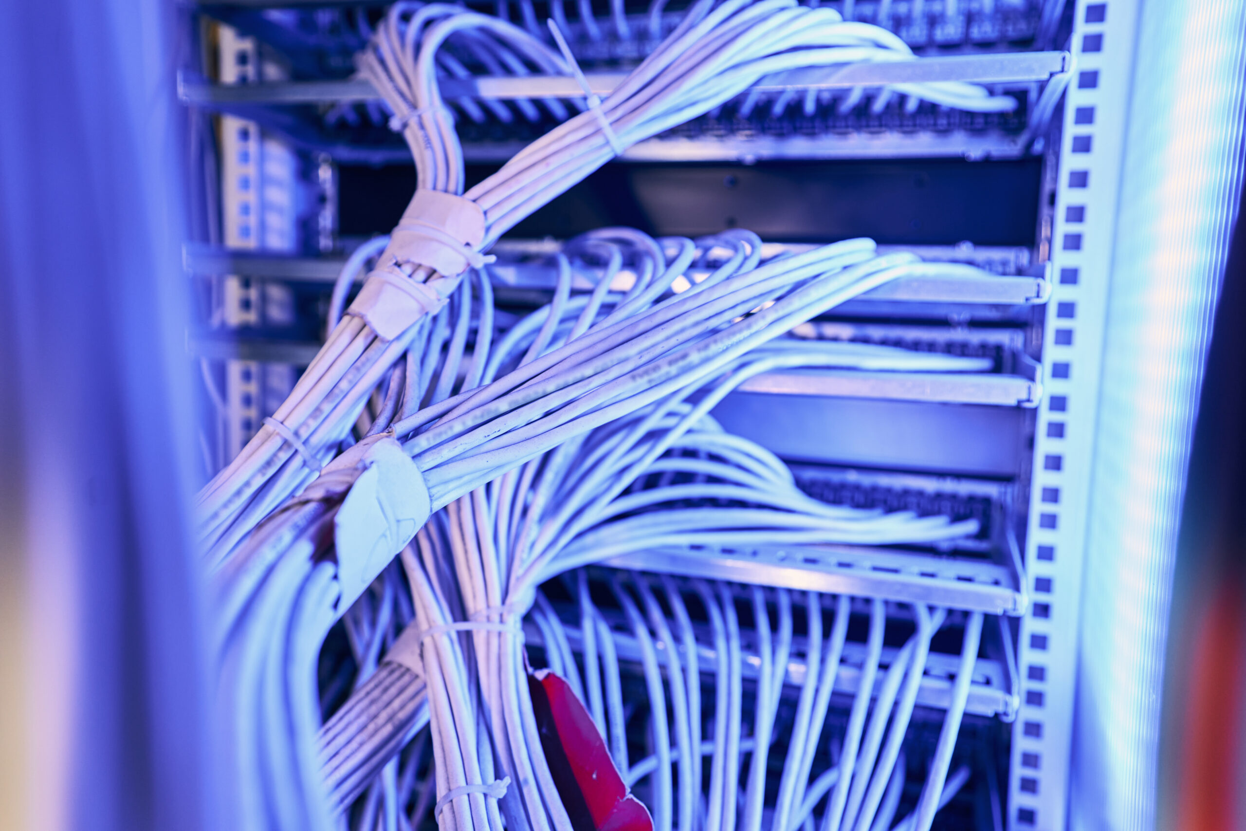 Structured network cabling infrastructure in server room Numerous network cables bundled with clear plastic tie wraps and plugged into ports on routers